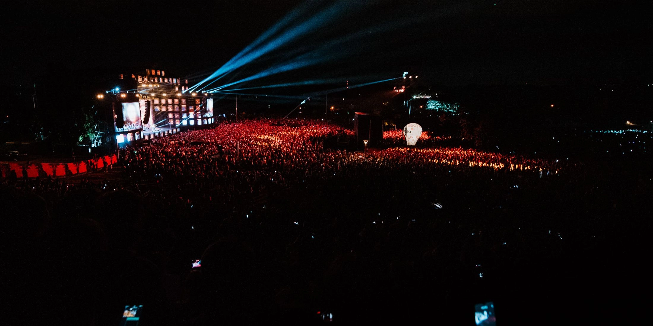 Koncert Wianki nad Wisłą w Warszawie, tłum publiczności i scena z reflektorami po zmroku.