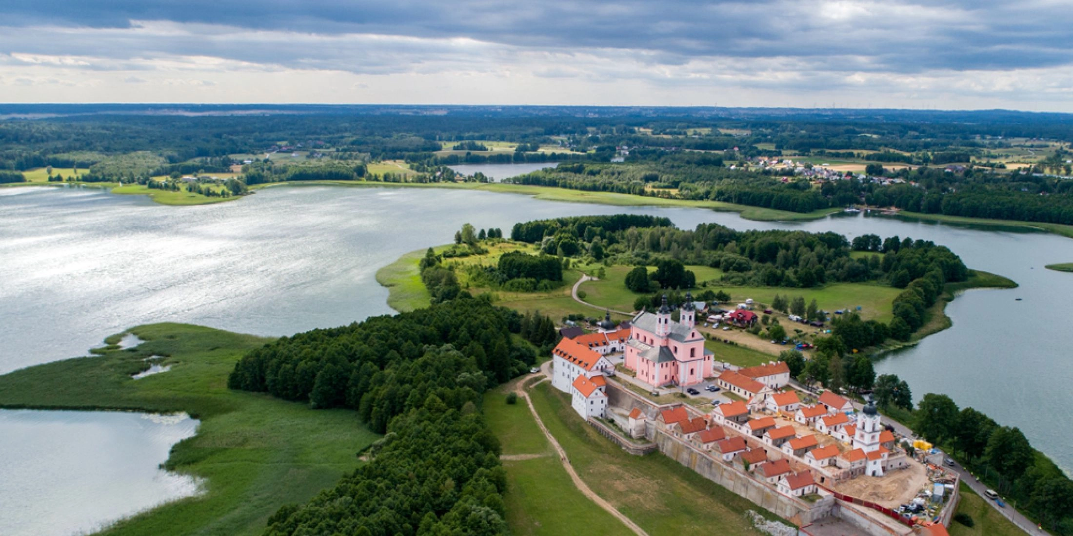 Widok z lotu ptaka na Pokamedulski Zespół Klasztorny w Wigrach, położony na półwyspie otoczonym wodami jeziora Wigry i zielenią.