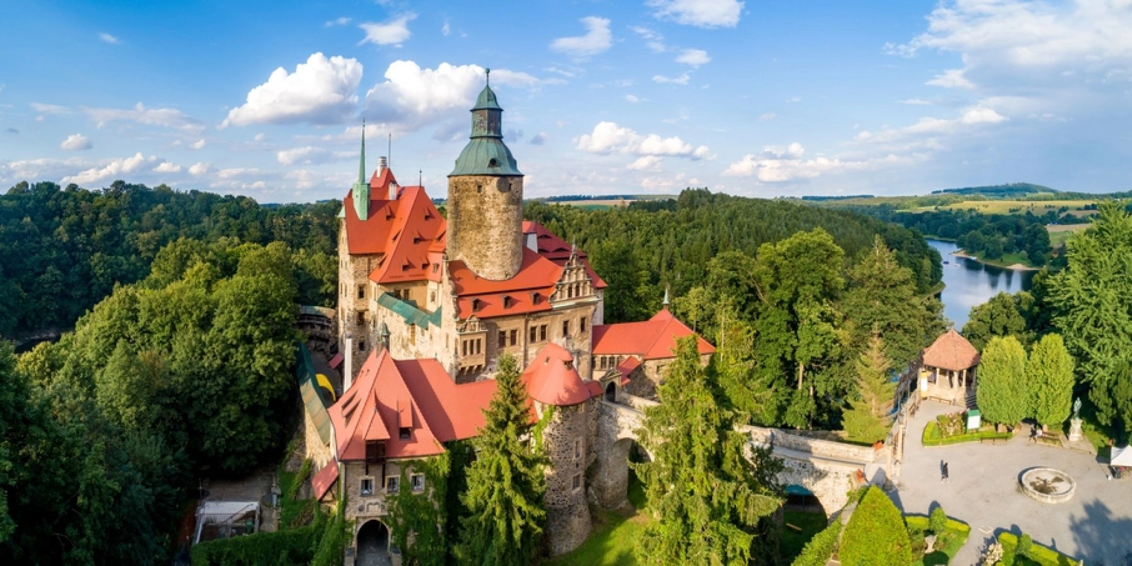 Widok z lotu ptaka na Zamek Czocha położony nad Jeziorem Leśniańskim i otoczony lasami.