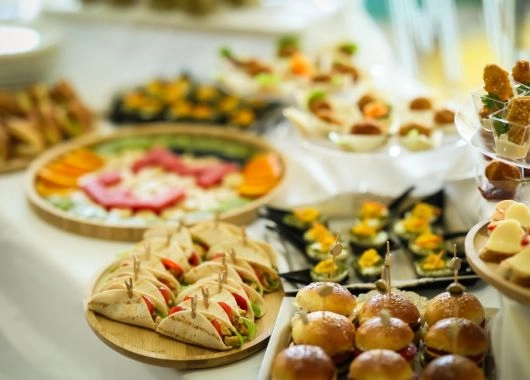 Mini burgery i tacos ułożone na drewnianych deskach jako nowoczesne przekąski na sylwestra.