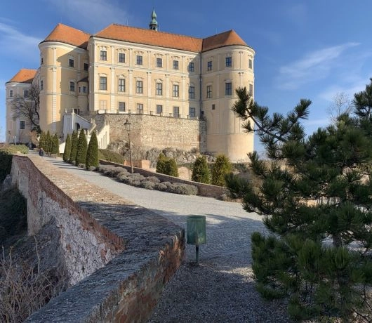 Zamek w Mikulovie z czerwonym dachem na wzgórzu z widokiem na miasteczko i winnice