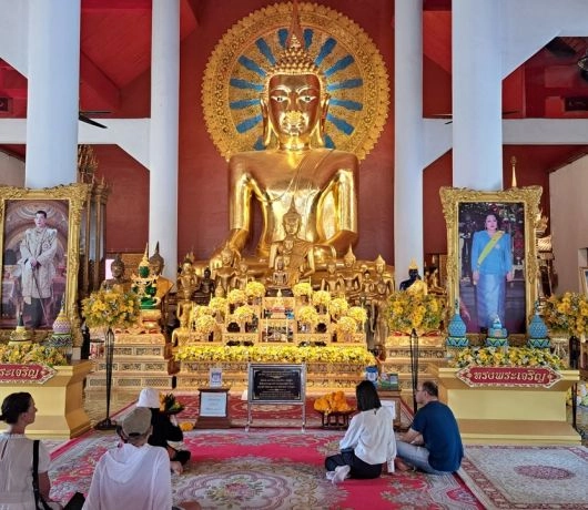 Złoty posąg Buddy w świątyni w Chiang Mai, wnętrze z modlącymi się ludźmi