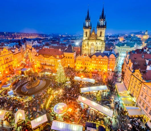 Panorama praskiego Rynku Staromiejskiego z choinką, straganami i kościołem Marii Panny przed Tynem o zmroku.