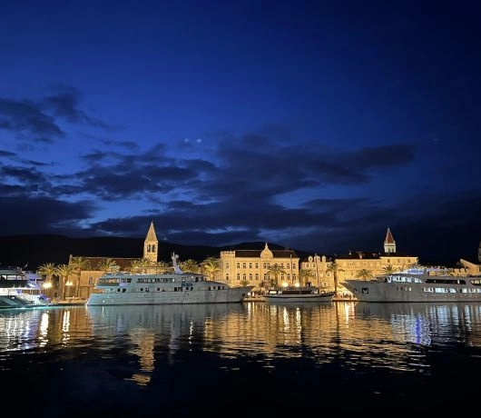 Nocny widok na port i oświetloną starówkę Trogiru w Chorwacji.