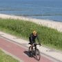 Rowerzysta jadący nadmorską trasą rowerową wzdłuż piaszczystej plaży i Bałtyku.