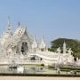 Wat Rong Khun w Chiang Rai, Biała Świątynia z rzeźbioną fasadą i mostem nad stawem, Tajlandia.