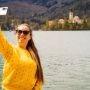 Alt: Kobieta robi selfie nad jeziorem z widokiem na wodę i góry podczas długiego weekendu w czerwcu.