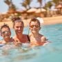 Kobieta z dwójką dzieci bawi się w wodzie przy hotelowej plaży w Egipcie.