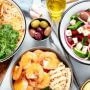 Grecka kuchnia i przekąski na stole: souvlaki, krewetki, sałatka grecka z fetą, oliwki i pita