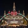 Plac przed wiedeńskim ratuszem z lodowiskiem i iluminacjami, świąteczne stoiska i odwiedzający po zmroku.