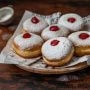 Tradycyjne pączki z różą posypane cukrem pudrem na drewnianym stole