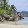 Plaża na wyspie Mahé z jasnym piaskiem, granitowymi skałami, palmami i spokojną wodą Oceanu Indyjskiego.