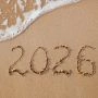 Napis 2026 na piasku nad brzegiem morza symbolizujący podróże.