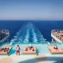 Błękitny basen infinity w strefie The Hideaway na rufie Legend of the Seas, z leżankami ustawionymi w wodzie i widokiem na morze oraz ratownikiem stojącym w wodzie.