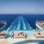 Błękitny basen infinity w strefie The Hideaway na rufie Legend of the Seas, z leżankami ustawionymi w wodzie i widokiem na morze oraz ratownikiem stojącym w wodzie.