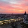 Centrum Suwałk widziane z góry o zachodzie słońca, z zabytkową zabudową, kościołem i różowym niebem nad miastem.