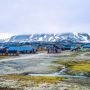 Kolorowe zabudowania Longyearbyen na Svalbardzie z ośnieżonymi górami w tle.