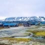 Kolorowe zabudowania Longyearbyen na Svalbardzie z ośnieżonymi górami w tle.