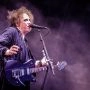 Wokalista The Cure śpiewa i gra na gitarze podczas koncertu