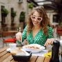 Kobieta siedzi przy stoliku w restauracyjnym ogródku i je makaron podczas kulinarnej podróży po Europie.