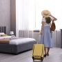 Kobieta z walizką w pokoju hotelowym podczas wakacyjnego wyjazdu