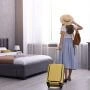 Kobieta z walizką w pokoju hotelowym podczas wakacyjnego wyjazdu
