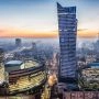 Warszawa z lotu ptaka o zmierzchu, skyline z wieżowcem Złota 44 i światłami miasta w tle.