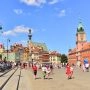 Plac Zamkowy i Stare Miasto w Warszawie w słoneczny dzień, spacerujący mieszkańcy i turyści.