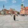 Plac Zamkowy w Warszawie z widokiem na Zamek Królewski, kolumnę Zygmunta i spacerujących turystów w majowy dzień.