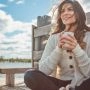 Kobieta odpoczywająca z kubkiem na pomoście nad jeziorem