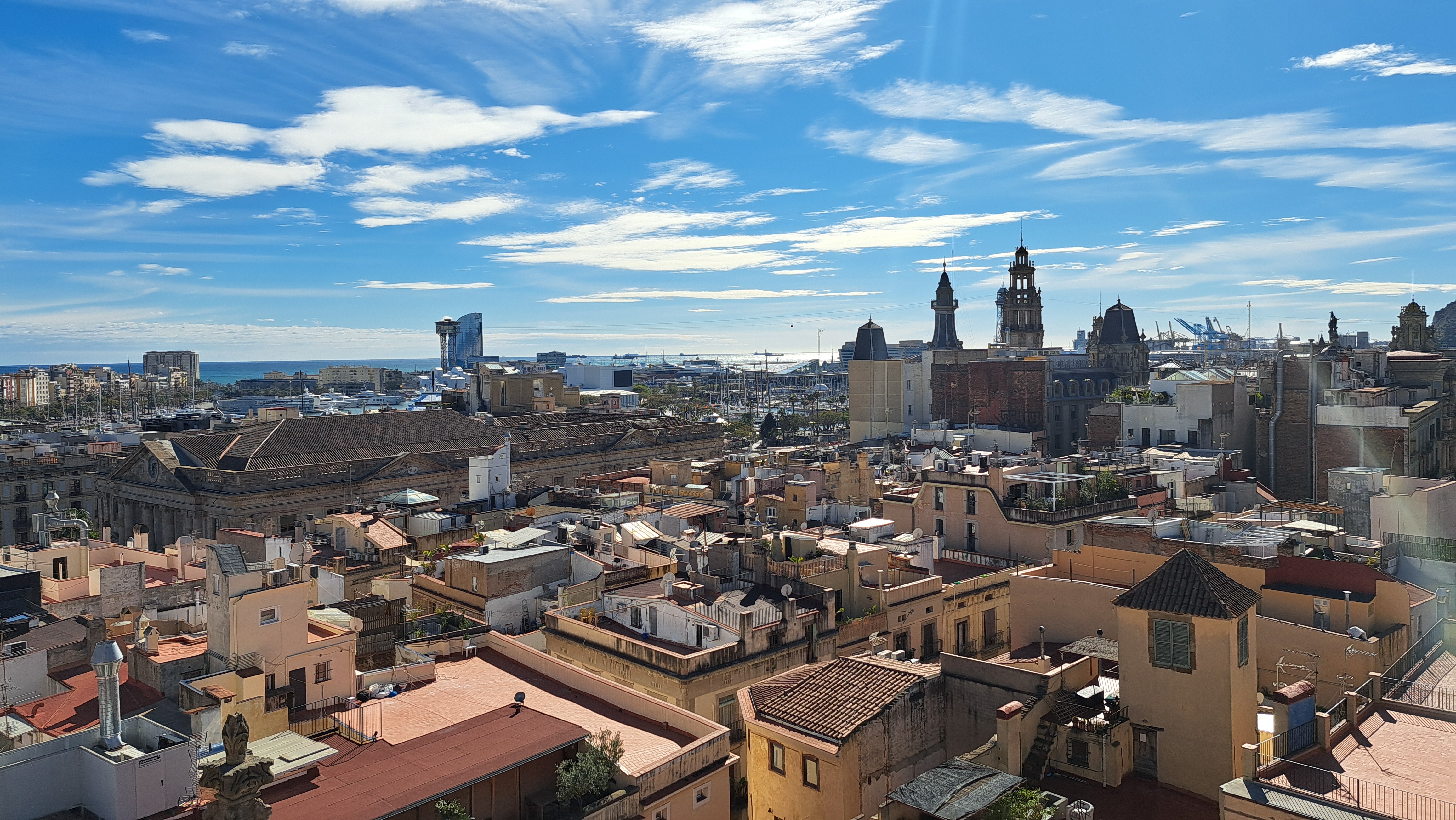 Panorama Barcelony z dachami starego miasta i portem nad Morzem Śródziemnym.