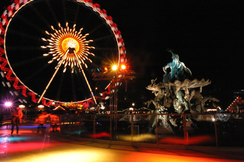 Diabelskie koło i lodowisko nocą na Alexanderplatz w Berlinie, oświetlone świątecznymi dekoracjami.