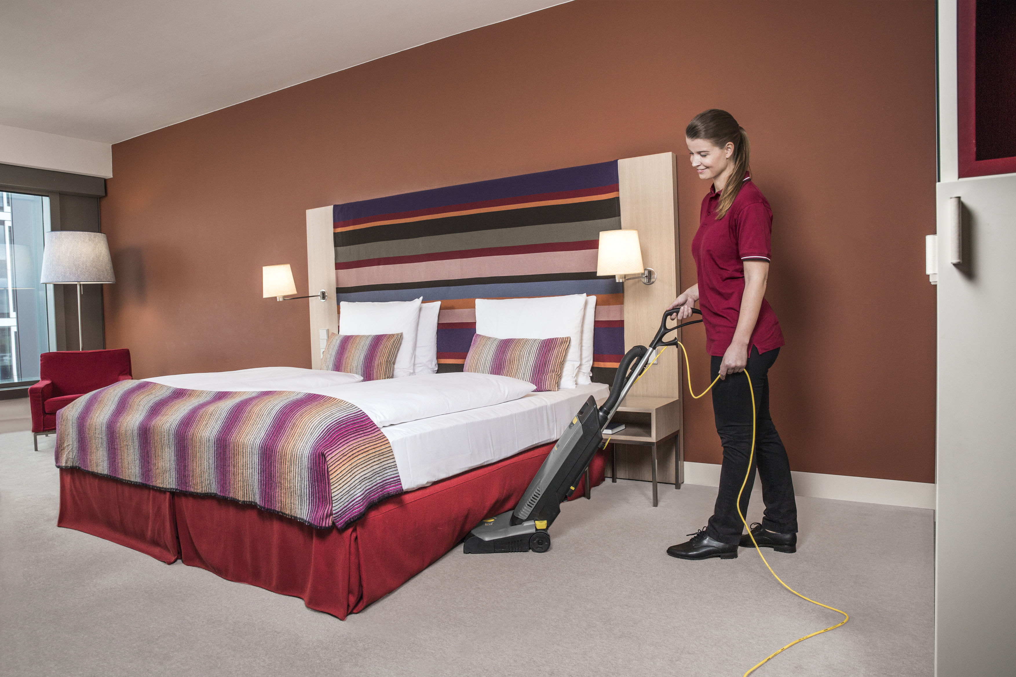 Pokojowa odkurzająca pokój hotelowy profesjonalnym odkurzaczem.