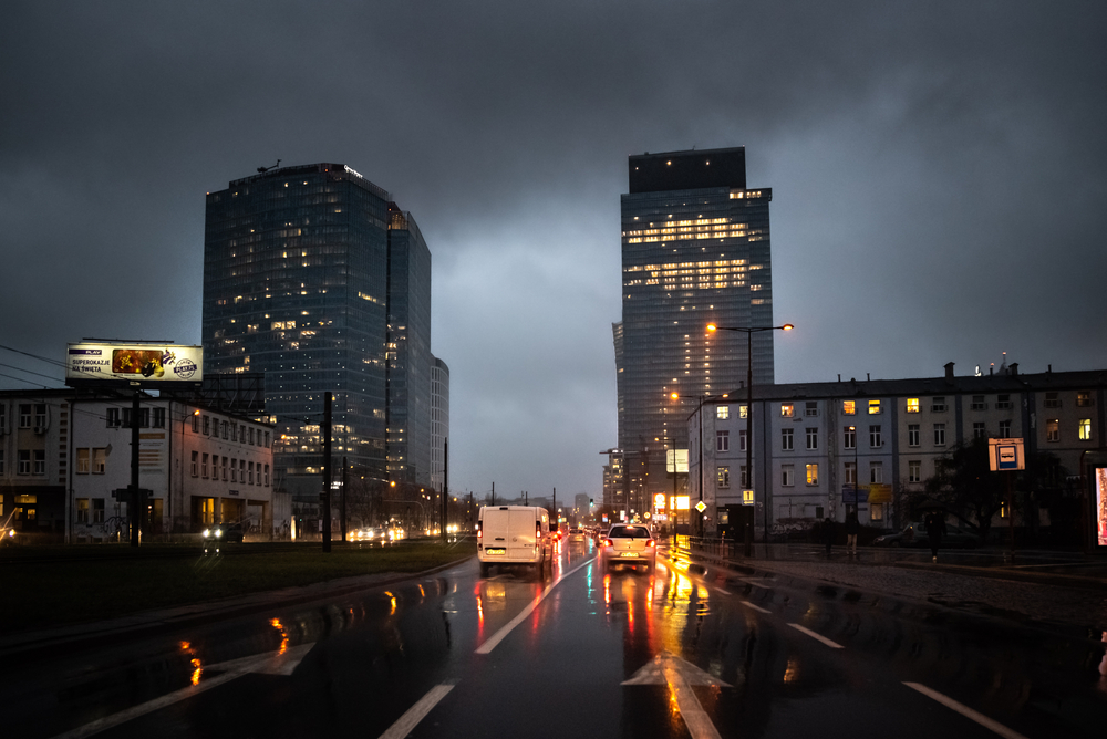 Nocny widok Warszawy po deszczu, biurowce i światła samochodów odbijające się w ulicy