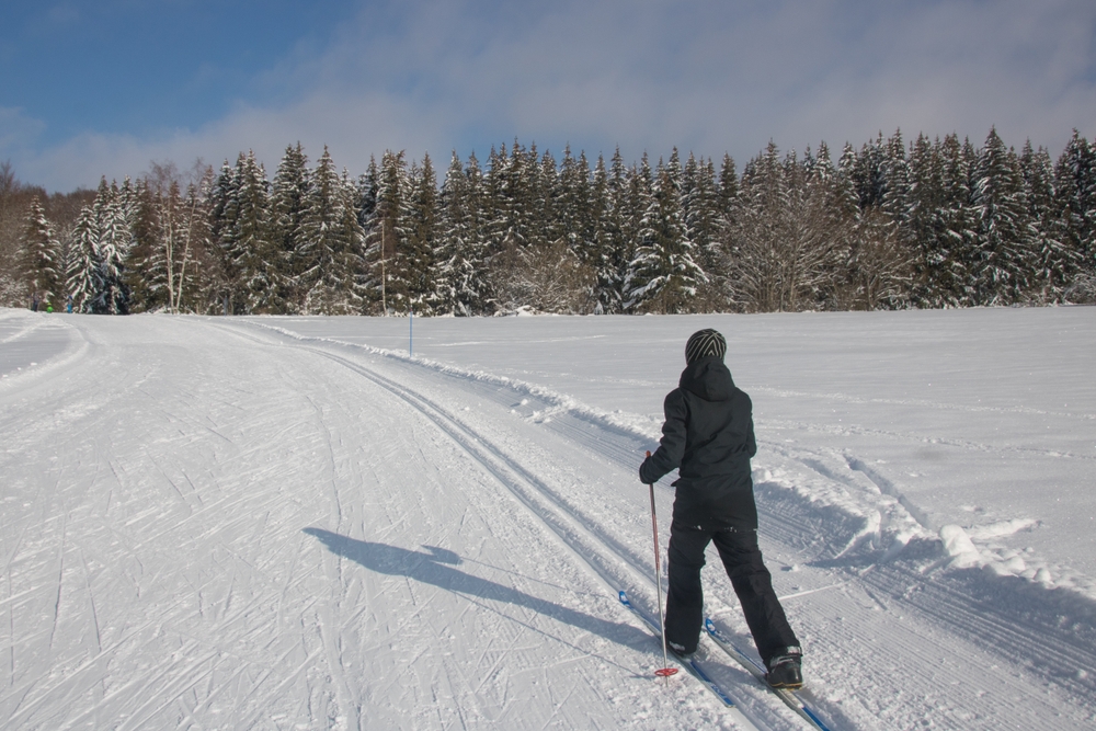 Kobieta na nartach biegowych na szerokiej, zaśnieżonej trasie w otwartym terenie zimą w Warszawie