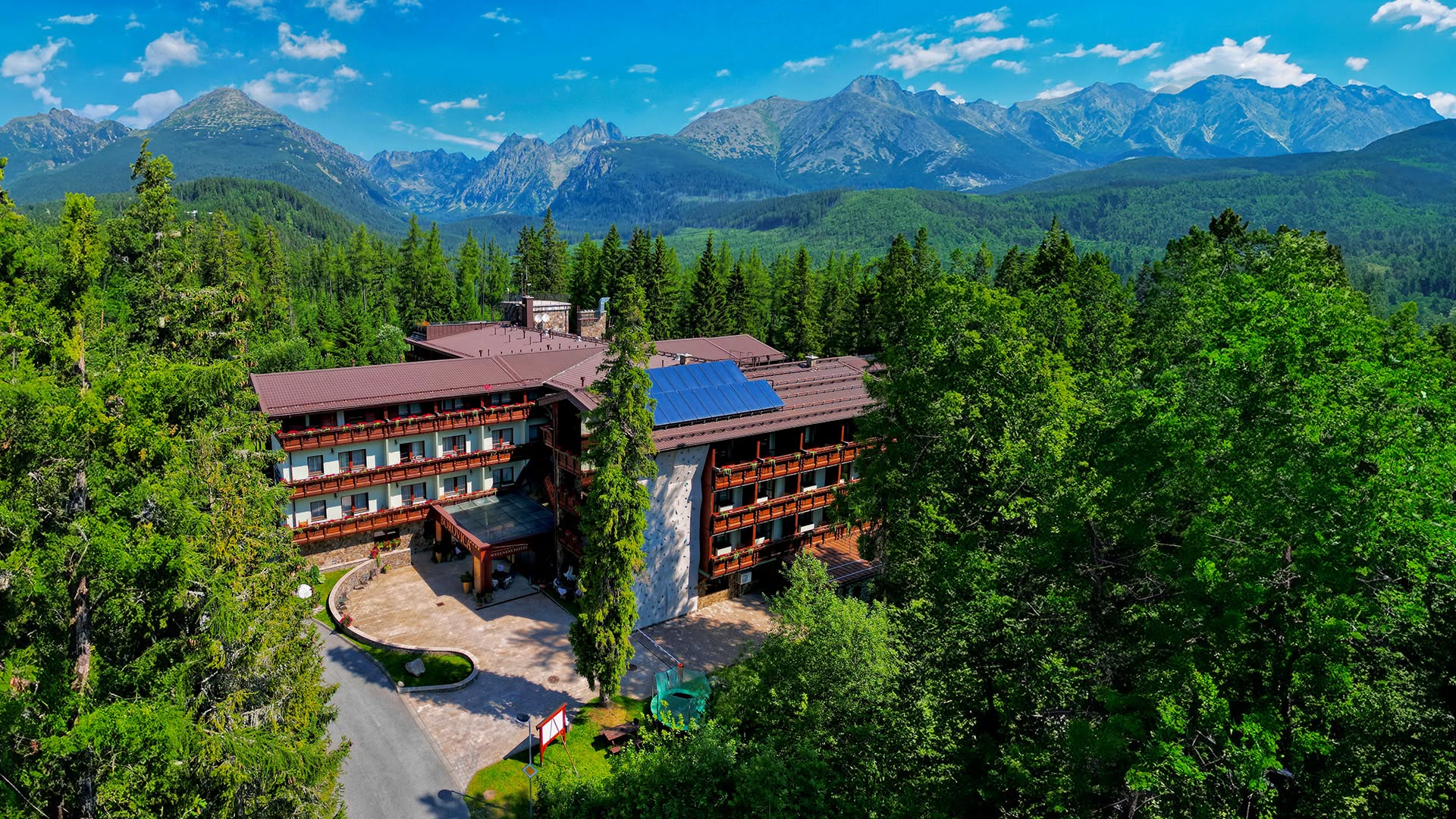 Hotel Borovica położony wśród lasów Štrbskiego Plesa na tle panoramy Tatr Wysokich.