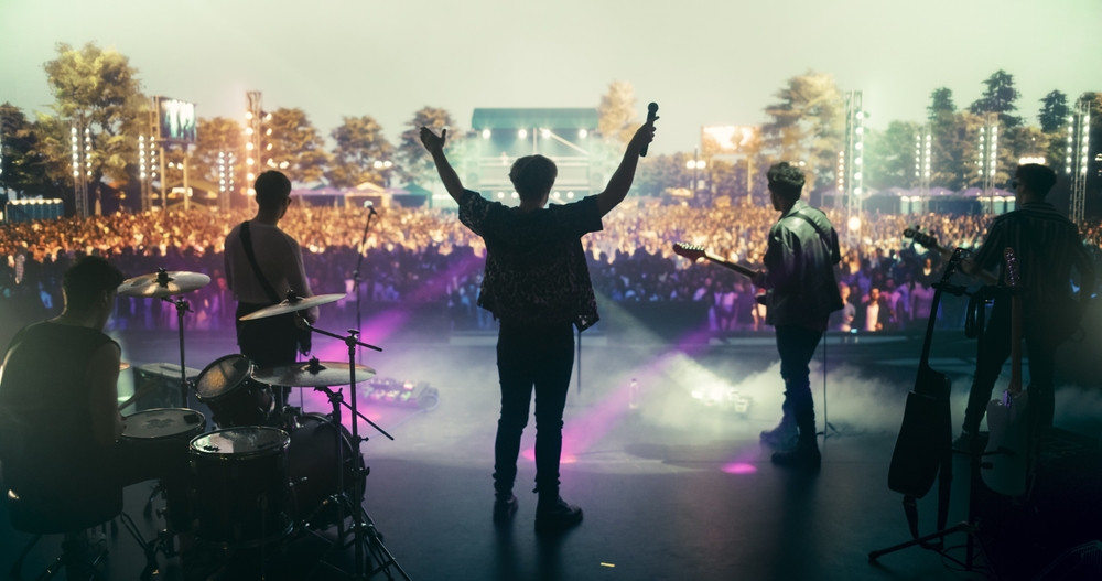 Zespół na scenie podczas plenerowego koncertu, przed sceną tłum publiczności