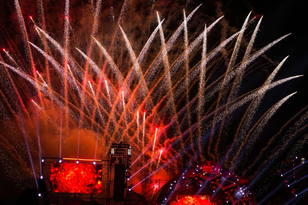 Plenerowy koncert sylwestrowy nocą, scena muzyczna i pokaz fajerwerków nad tłumem uczestników.