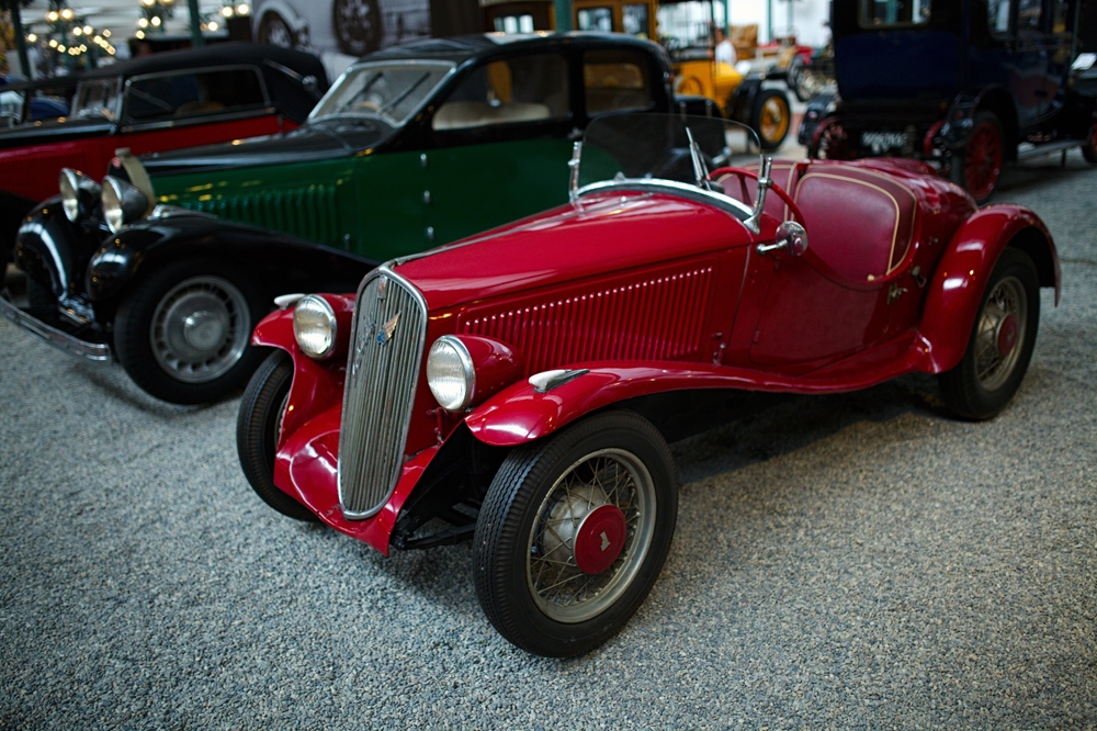 Czerwony zabytkowy samochód sportowy z lat 20. XX wieku na ekspozycji Narodowego Muzeum Motoryzacji w Miluzie, prezentowany wśród klasycznych europejskich modeli.