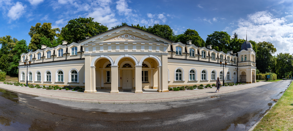 Jasna, rozległa fasada Sanatorium Książę Józef w Parku Zdrojowym w Nałęczowie z arkadowym wejściem i narożną wieżyczką.