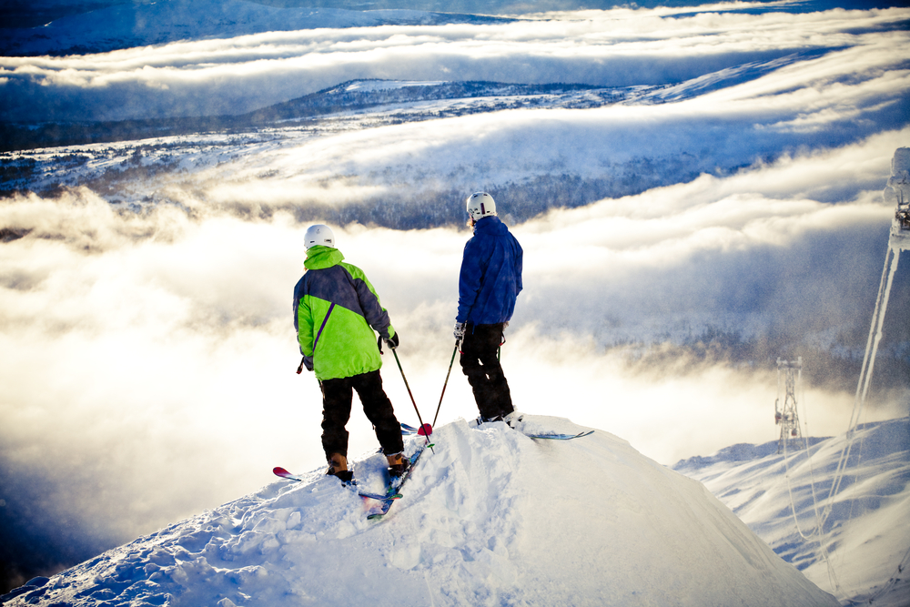 Dwóch narciarzy na szczycie ośrodka Åre w Szwecji patrzy na morze chmur i ośnieżone góry