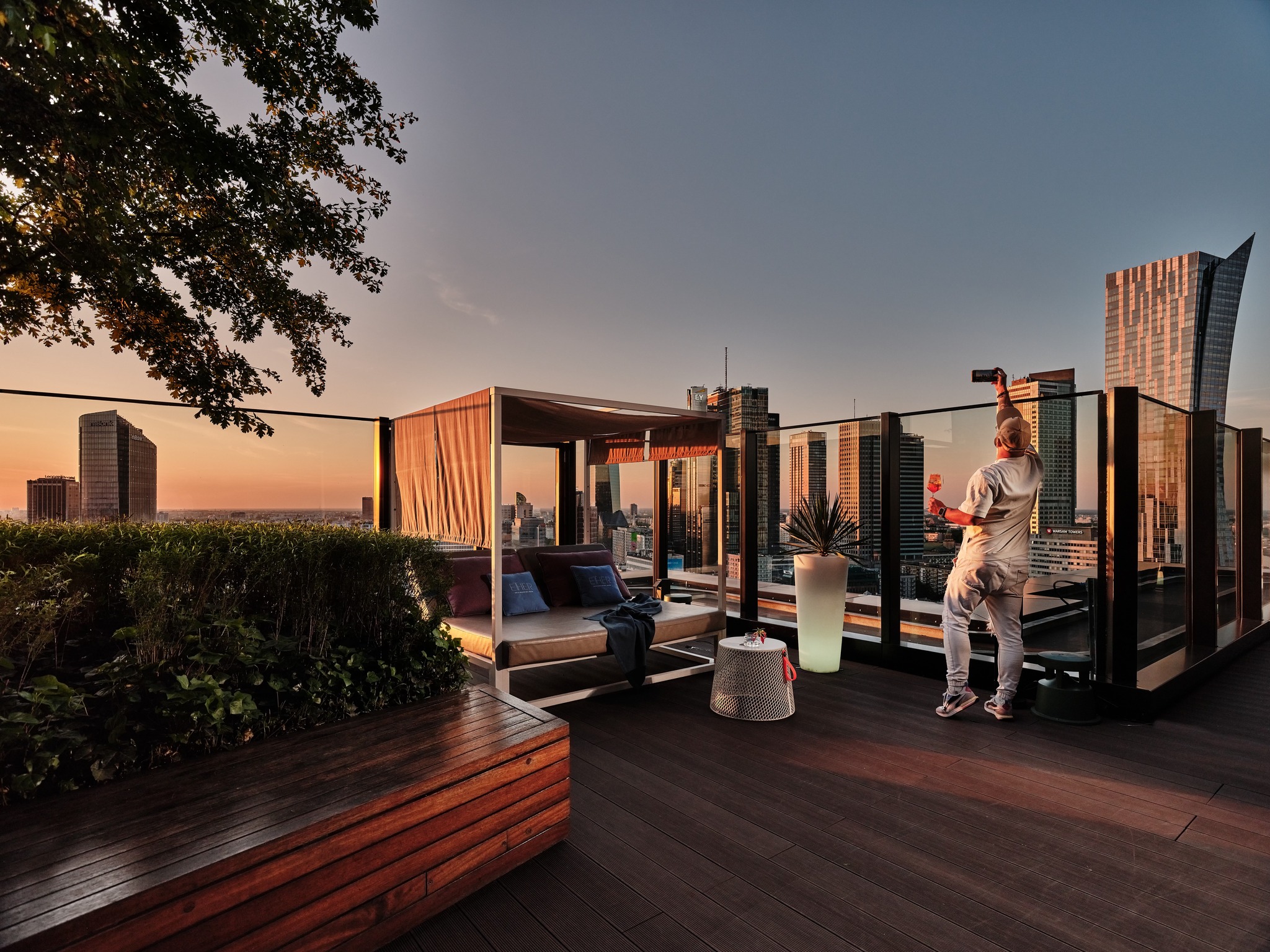 Taras Ether Rooftop Bar w Warszawie z widokiem na wieżowce centrum miasta o zachodzie słońca.