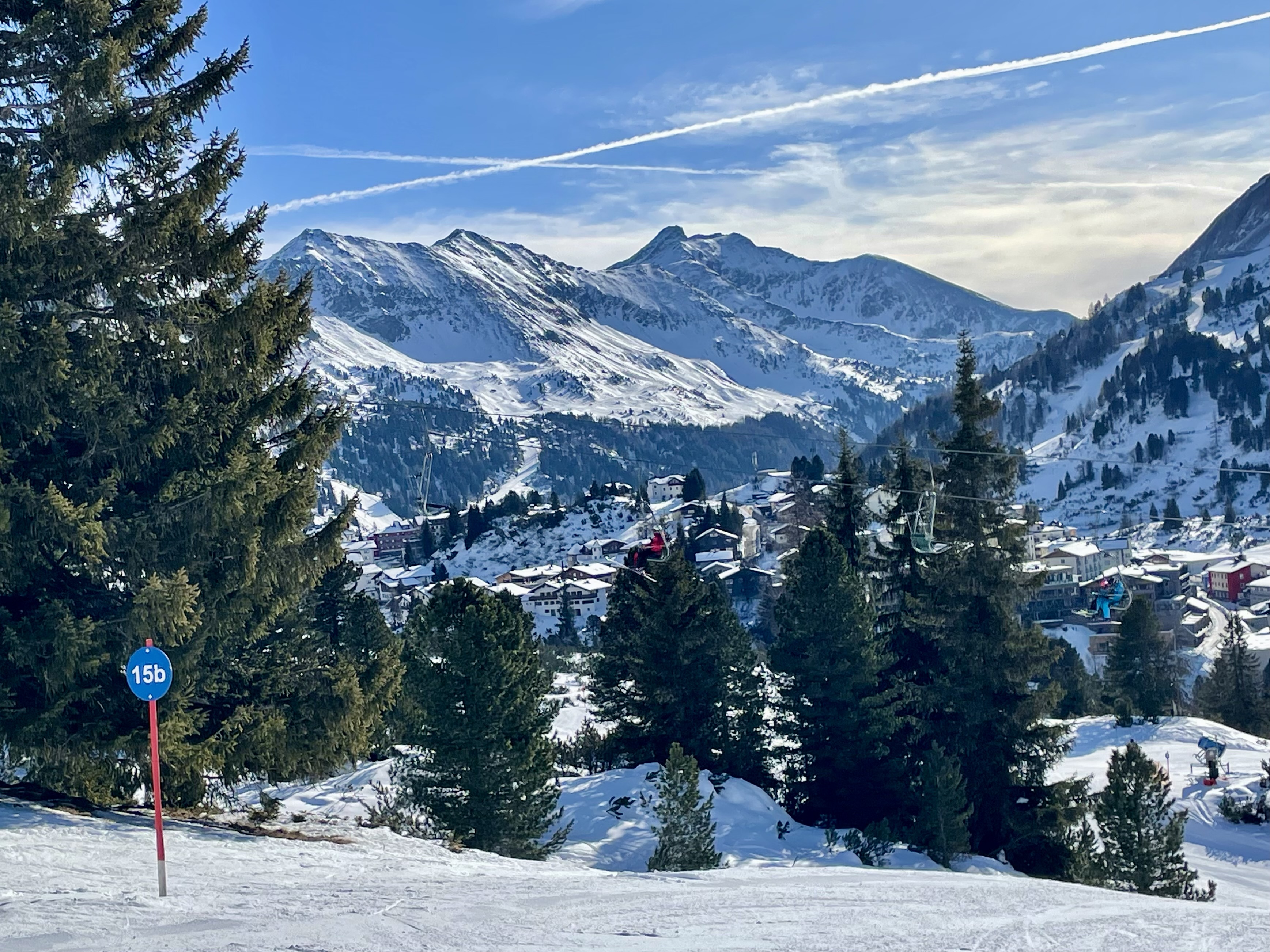 Widok na miejscowość Obertauern z trasy narciarskiej, oznaczenie 15b i alpejska panorama w tle