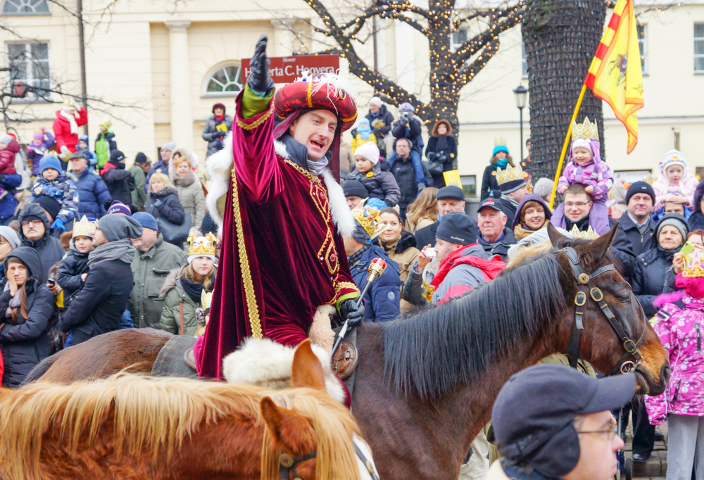 Postać Trzech Króli na koniu podczas Orszaku Trzech Króli w Warszawie, tłum uczestników w zimowych kurtkach i papierowych koronach