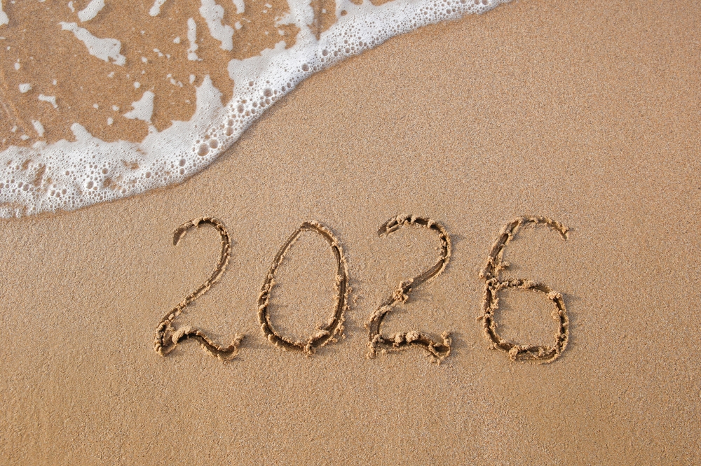 Napis 2026 na piasku nad brzegiem morza symbolizujący podróże.