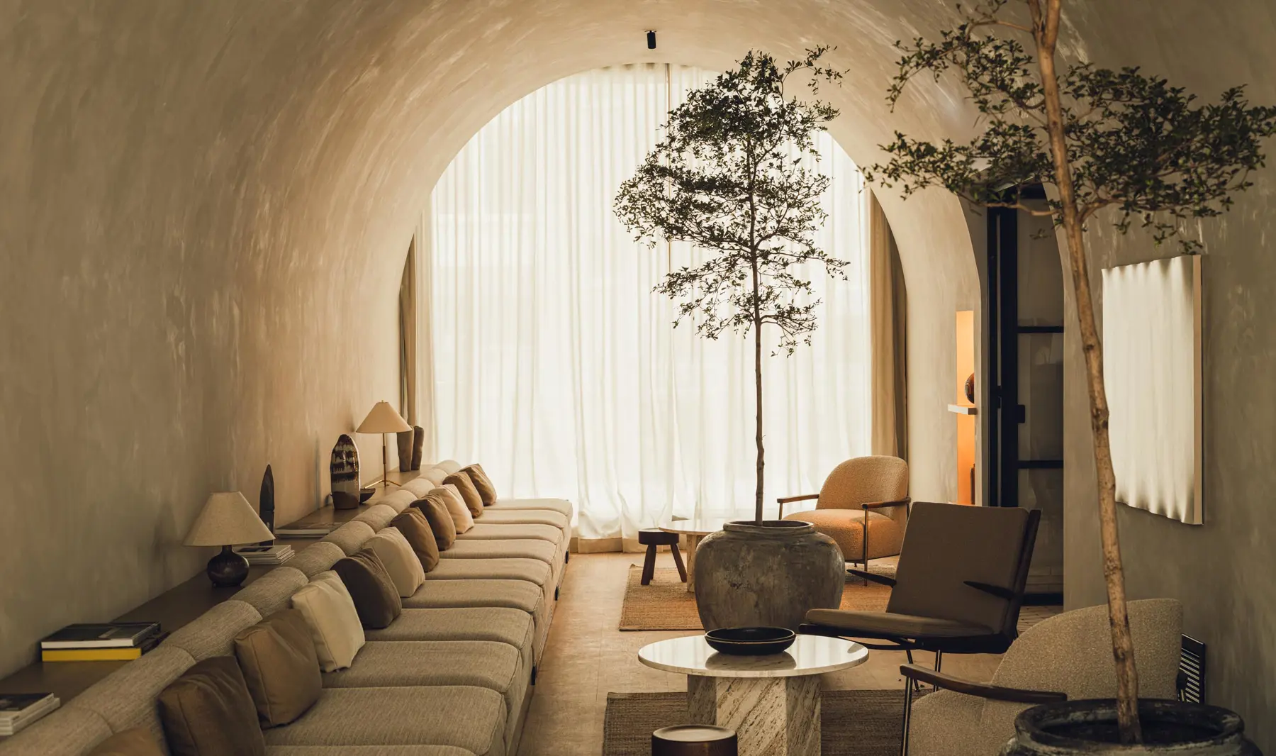 Strefa lounge w hotelu PURO Warszawa Stare Miasto z długą sofą, fotelami i drzewem w donicy, projekt wnętrz GamFratesi