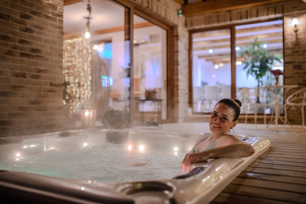Kobieta relaksująca się w jacuzzi w hotelowym spa w zimowej atmosferze.