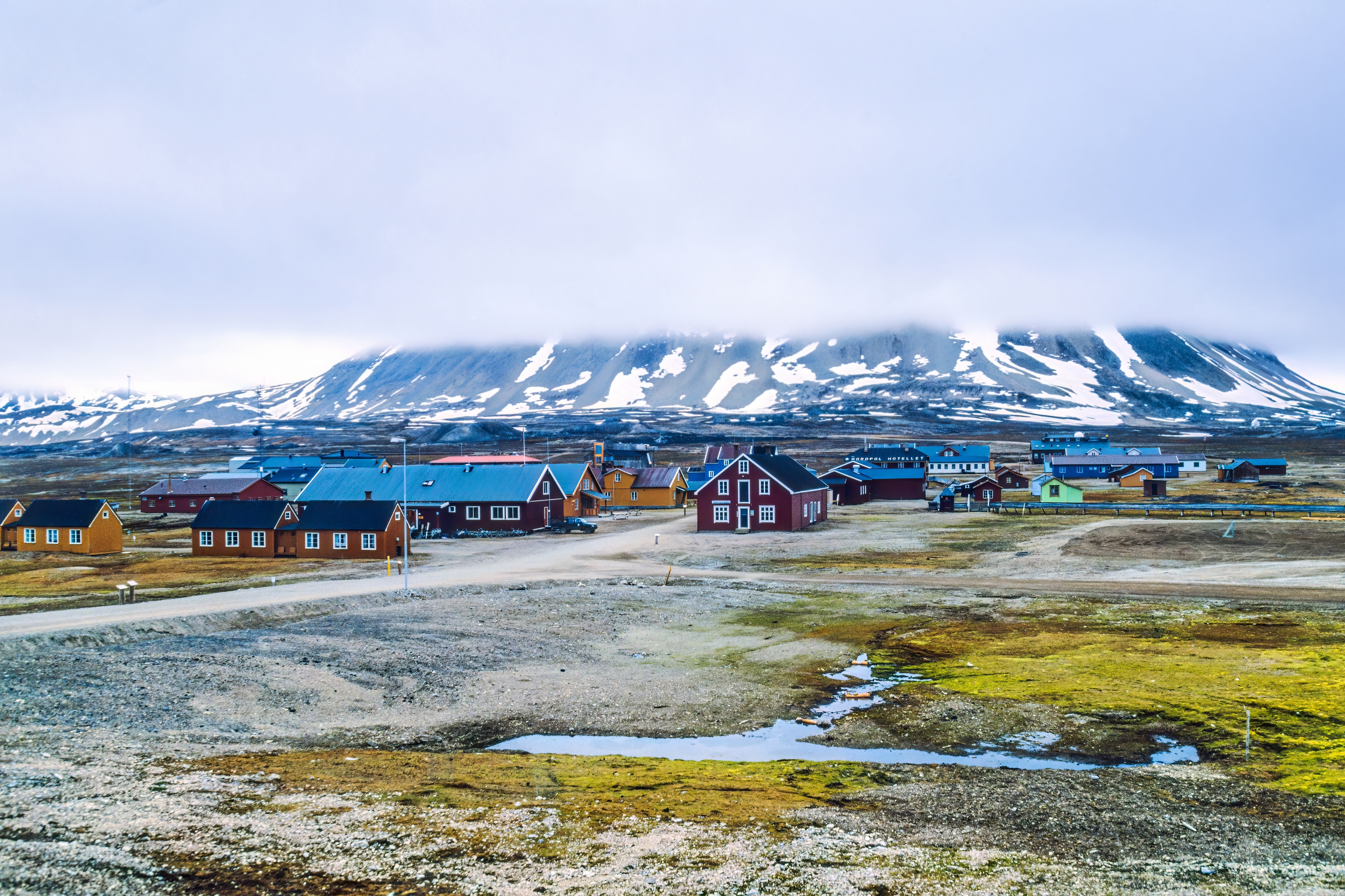 Kolorowe zabudowania Longyearbyen na Svalbardzie z ośnieżonymi górami w tle.
