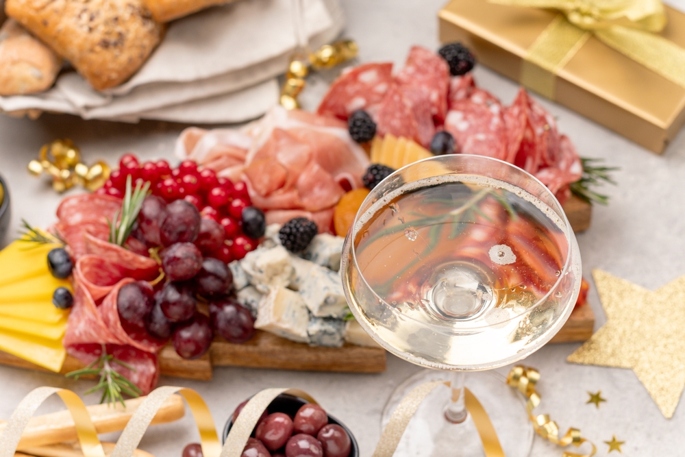 Deska z serami, wędlinami i przekąskami podana jako elegancki sylwestrowy poczęstunek.