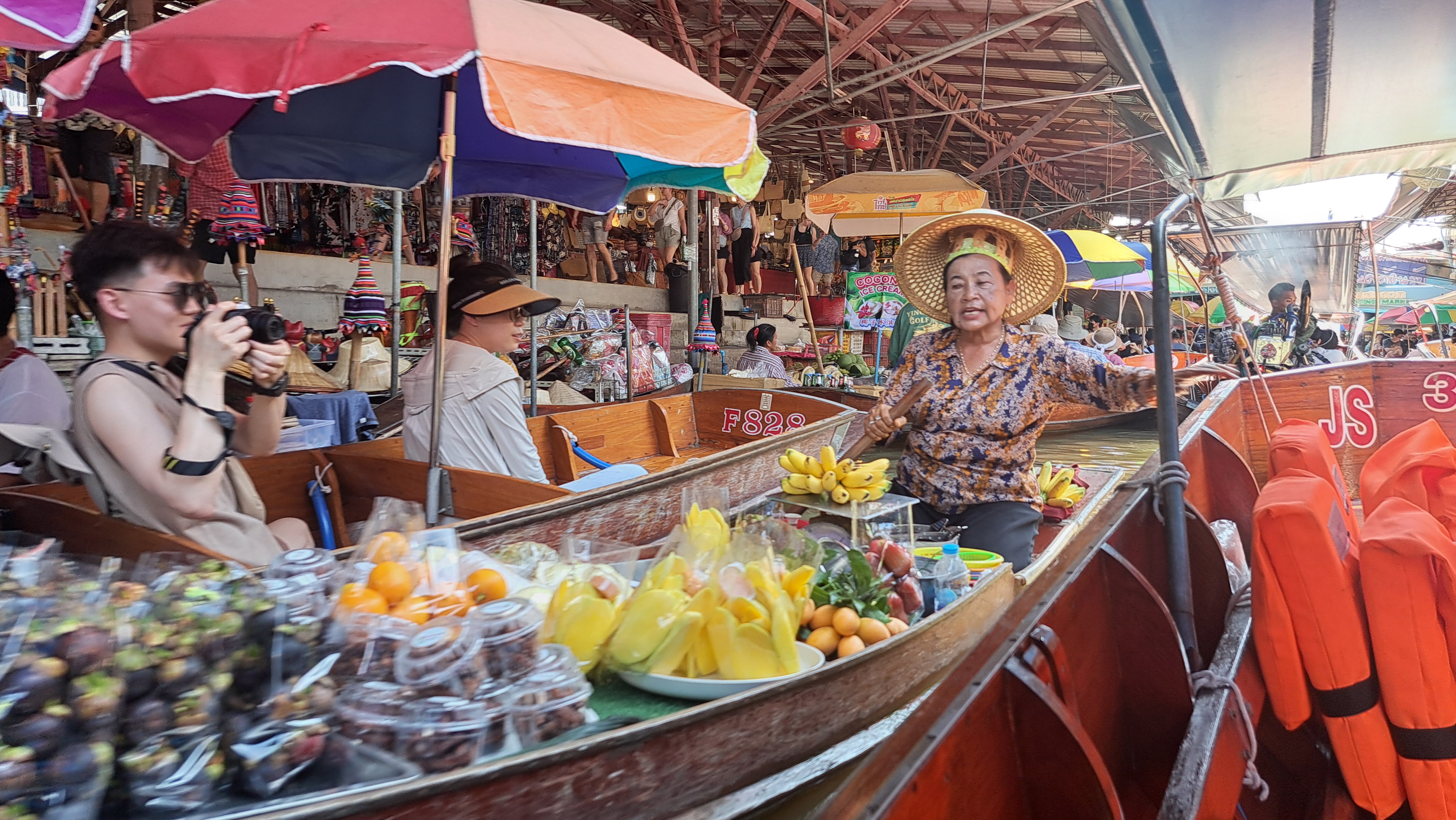 Tajski targ wodny, sprzedawczyni owoców na drewnianej łodzi, codzienne życie i lokalna kuchnia Tajlandii.